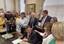 Governor Meyer signs the Ron Silverio/Heather Block Delaware End-of-Life Options Act into law surrounded by advocates and legislative champions on May 20.
