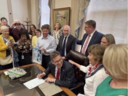 Governor Meyer signs the Ron Silverio/Heather Block Delaware End-of-Life Options Act into law surrounded by advocates and legislative champions on May 20.